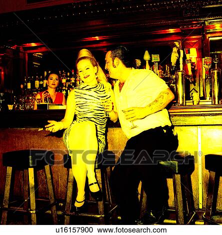 Stock Image - Mid adult couple sitting at a bar counter. Fotosearch