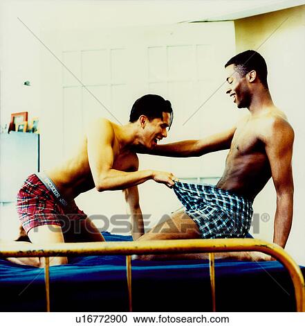 Stock Image - Young man looking into another young man's underwear. Fotosearch
