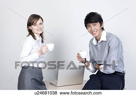 Stock Photo - Business people holding coffee cups and smiling at the camera. Fotosearch