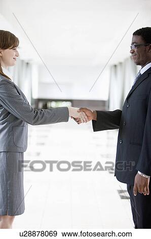 Business people of different colors shaking hands together and smiling View Large Photo Image Stock Photo - Business people of different colors shaking hands together and smiling. Fotosearch