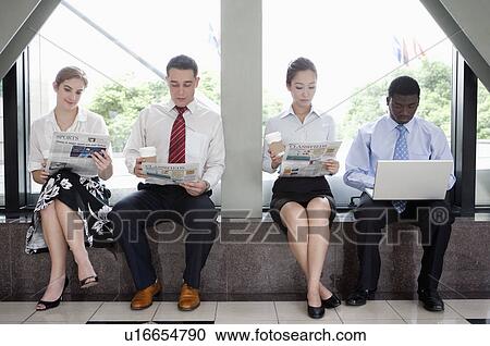 Stock Image - Business people reading a newspaper or using laptop to have a rest. Fotosearch