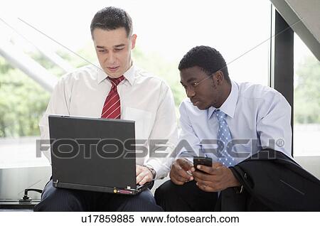 Business people sitting and looking at the laptop together View Large Photo Image Stock Photography - Business people sitting and looking at the laptop together. Fotosearch