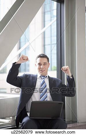Stock Photo - Business people sitting with laptop and raising fists with confidence. Fotosearch