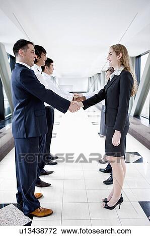 Business people standing in a row and shaking hands together View Large Photo Image Stock Image - Business people standing in a row and shaking hands together. Fotosearch