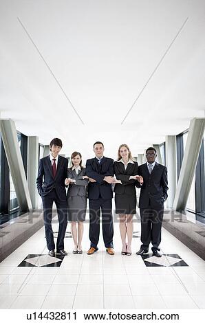 Stock Image - Business people standing in a row and clasping hands together. Fotosearch