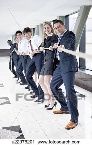 Stock Image - Business people standing in a row and playing tug-of war. Fotosearch