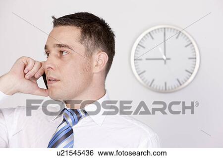 Stock Photograph - Business people using mobile phone and looking away. Fotosearch