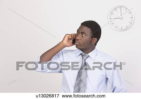 Businessman holding a mobile phone and looking away at 9 o'clock View Large Photo Image Stock Photo - Businessman holding a mobile phone and looking away at 9 o'clock. Fotosearch