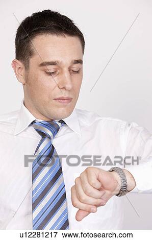Stock Photo - Businessman looking down and watching for the time. Fotosearch