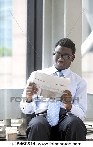 Businessman sitting and reading a newspaper View Large Photo Image Picture - Businessman sitting and reading a newspaper. Fotosearch
