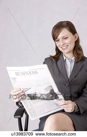 Businesswoman sitting in a chair and reading a newspaper with smile View Large Photo Image Stock Photo - Businesswoman sitting in a chair and reading a newspaper with smile. Fotosearch