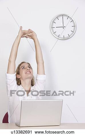 Stock Image - Businesswoman stretching and looking up at 9 o'clock. Fotosearch