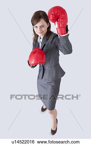 Businesswoman looking up and wearing boxing glove with smile View Large Photo Image Stock Photograph - Businesswoman looking up and wearing boxing glove with smile. Fotosearch