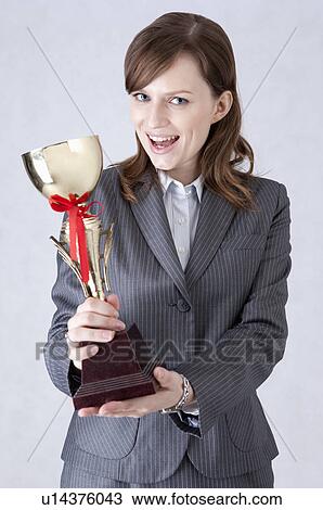 Businesswoman showing a trophy and smiling View Large Photo Image Stock Image - Businesswoman showing a trophy and smiling. Fotosearch