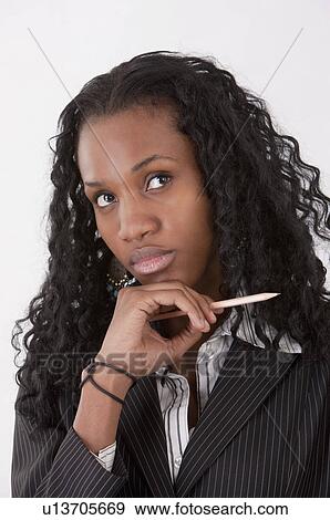 Stock Photo - Close-up of businesswoman holding a pencil and looking up. Fotosearch