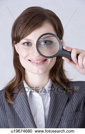Close-up of businesswoman putting a magnifying glass on one eye and smiling View Large Photo Image Stock Image - Close-up of businesswoman putting a magnifying glass on one eye and smiling. Fotosearch