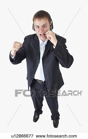 Stock Photo - Young businessman shouting with fists up and wearing headset. Fotosearch