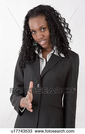 Stock Image - Young businesswoman reaching one hand and smiling at the camera. Fotosearch