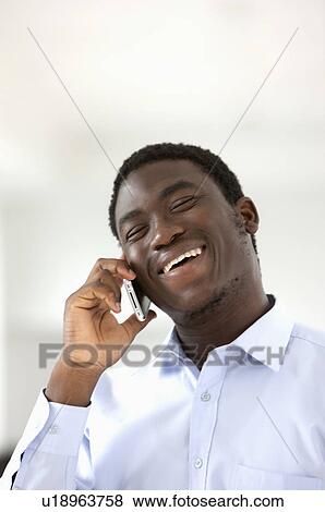 Young man holding mobile phone and smiling happily View Large Photo Image Stock Photo - Young man holding mobile phone and smiling happily. Fotosearch