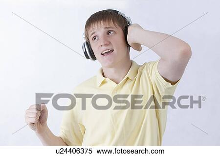 Stock Photography - Young man listening music with headset and looking up. Fotosearch