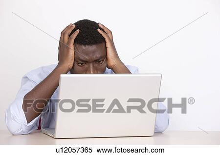 Young man looking at laptop and putting hands on head of anxiety View Large Photo Image Stock Photography - Young man looking at laptop and putting hands on head of anxiety. Fotosearch