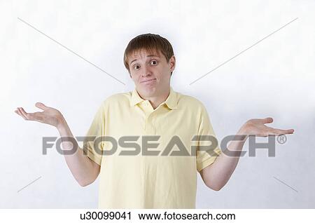 Stock Image - Young man shrugging and looking at the camera with helpless gesture. Fotosearch