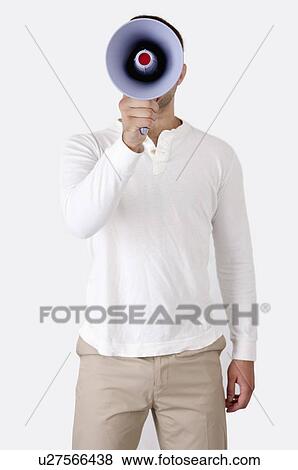 Stock Photo - Young man standing and holding megaphone. Fotosearch