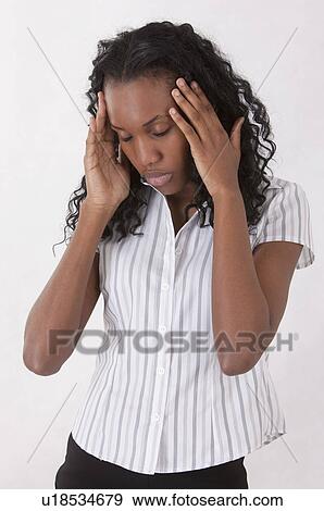 Stock Photo - Young woman looking down with head in hands and closing her eyes. Fotosearch