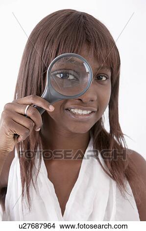 Young woman putting magnifying glass on one eye and smiling View Large Photo Image Picture - Young woman putting magnifying glass on one eye and smiling. Fotosearch