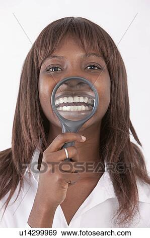Young woman putting magnifying glass on her teeth and smiling View Large Photo Image Stock Photo - Young woman putting magnifying glass on her teeth and smiling. Fotosearch