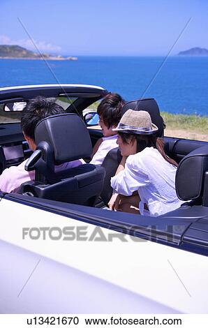 Stock Image - Three people driving in the car and enjoying leisure activity together. Fotosearch