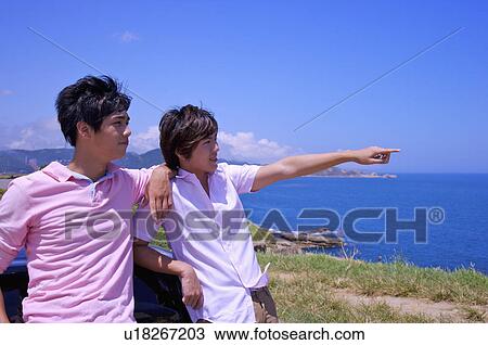 Stock Image - Two men standing together and pointing away. Fotosearch