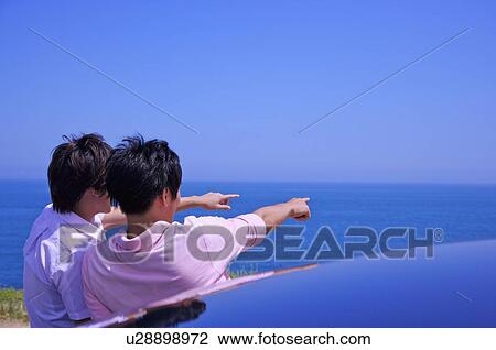 Stock Image - Two men standing together and pointing away. Fotosearch