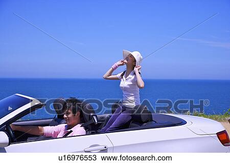 Stock Image - Young couple driving in the car and enjoying leisure activity together. Fotosearch