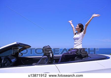 Young woman sitting in the car with arms outstretched and looking up View Large Photo Image Stock Image - Young woman sitting in the car with arms outstretched and looking up. Fotosearch