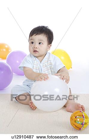 Baby boy sitting on the floor with balloon and looking away View Large Photo Image Stock Photo - Baby boy sitting on the floor with balloon and looking away. Fotosearch