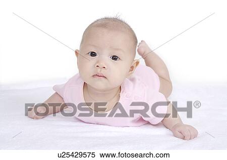 Stock Photography - Baby girl lying on front and looking at the camera. Fotosearch