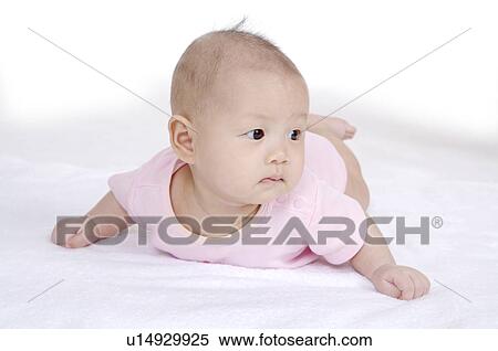 Stock Photography - Baby girl lying on front and looking away. Fotosearch