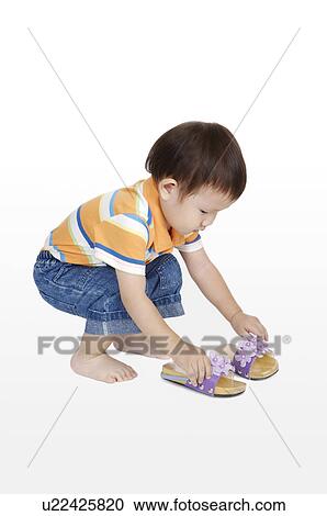 Little boy crouching and holding shoes View Large Photo Image Stock Image - Little boy crouching and holding shoes. Fotosearch
