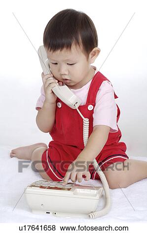 Little boy sitting and playing with telephone View Large Photo Image Stock Photo - Little boy sitting and playing with telephone. Fotosearch