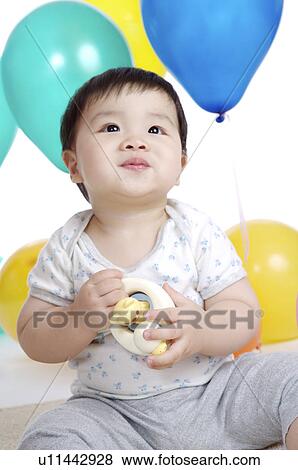 Little boy sitting, holding a toy and looking up View Large Photo Image Stock Photo - Little boy sitting, holding a toy and looking up. Fotosearch