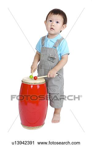 Stock Image - Little boy standing and playing drum. Fotosearch