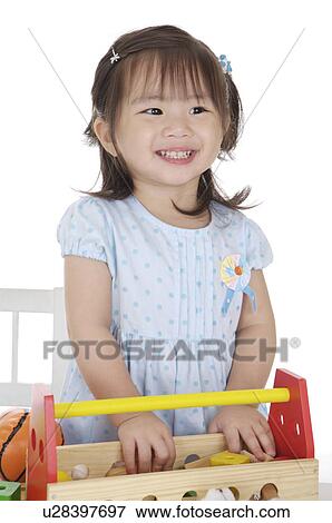 Stock Photo - Little girl playing with desk toy and looking away with smile. Fotosearch