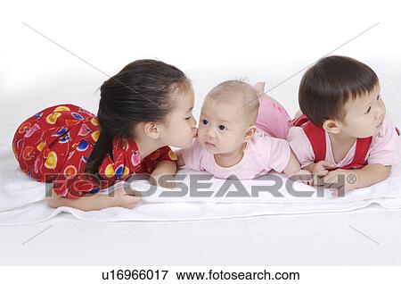 Stock Photo - Three children lying on front together and looking away. Fotosearch