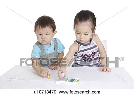 Stock Image - Two children drawing and looking down together. Fotosearch