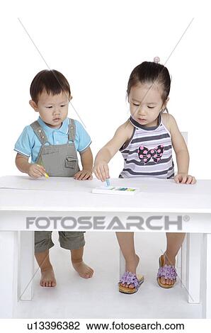 Stock Image - Two children drawing and looking down together. Fotosearch