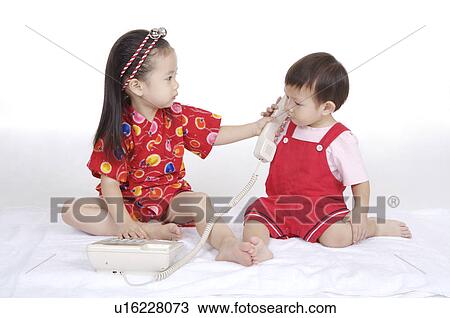 Two children sitting and playing together with telephone View Large Photo Image Stock Image - Two children sitting and playing together with telephone. Fotosearch