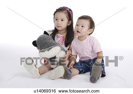 Stock Photograph - Two children sitting on the floor together and looking away. Fotosearch