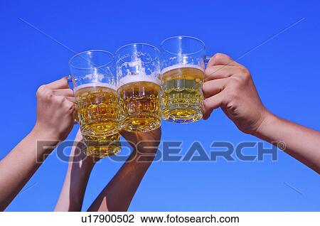 Stock Image - Close-up of hands holding beer and toasting,. Fotosearch