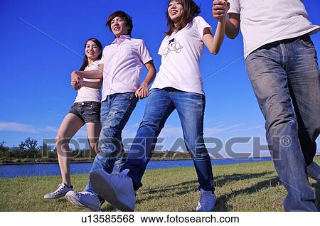 Four people holding hands together and walking on the lawn, View Large Photo Image Stock Photo - Four people holding hands together and walking on the lawn,. Fotosearch